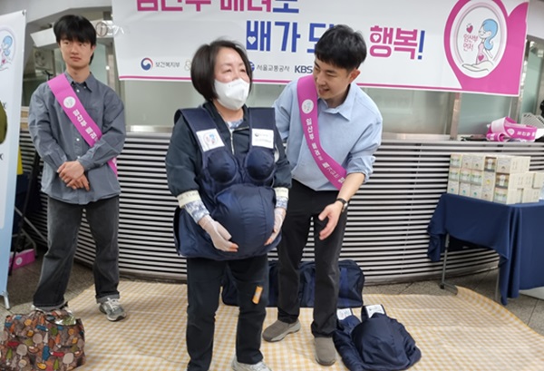시민들이 직접 착용해 보며 임산부의 어려움을 체험해 보고 있다